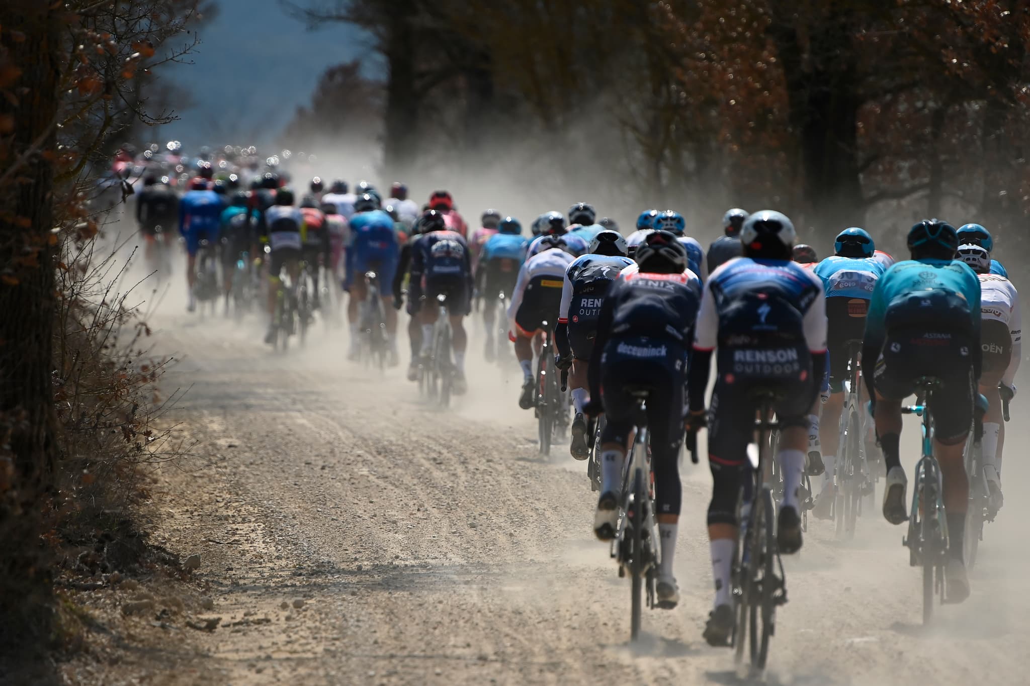 Peloton on gravel road, Alpecin-Deceuninck, Astana visible