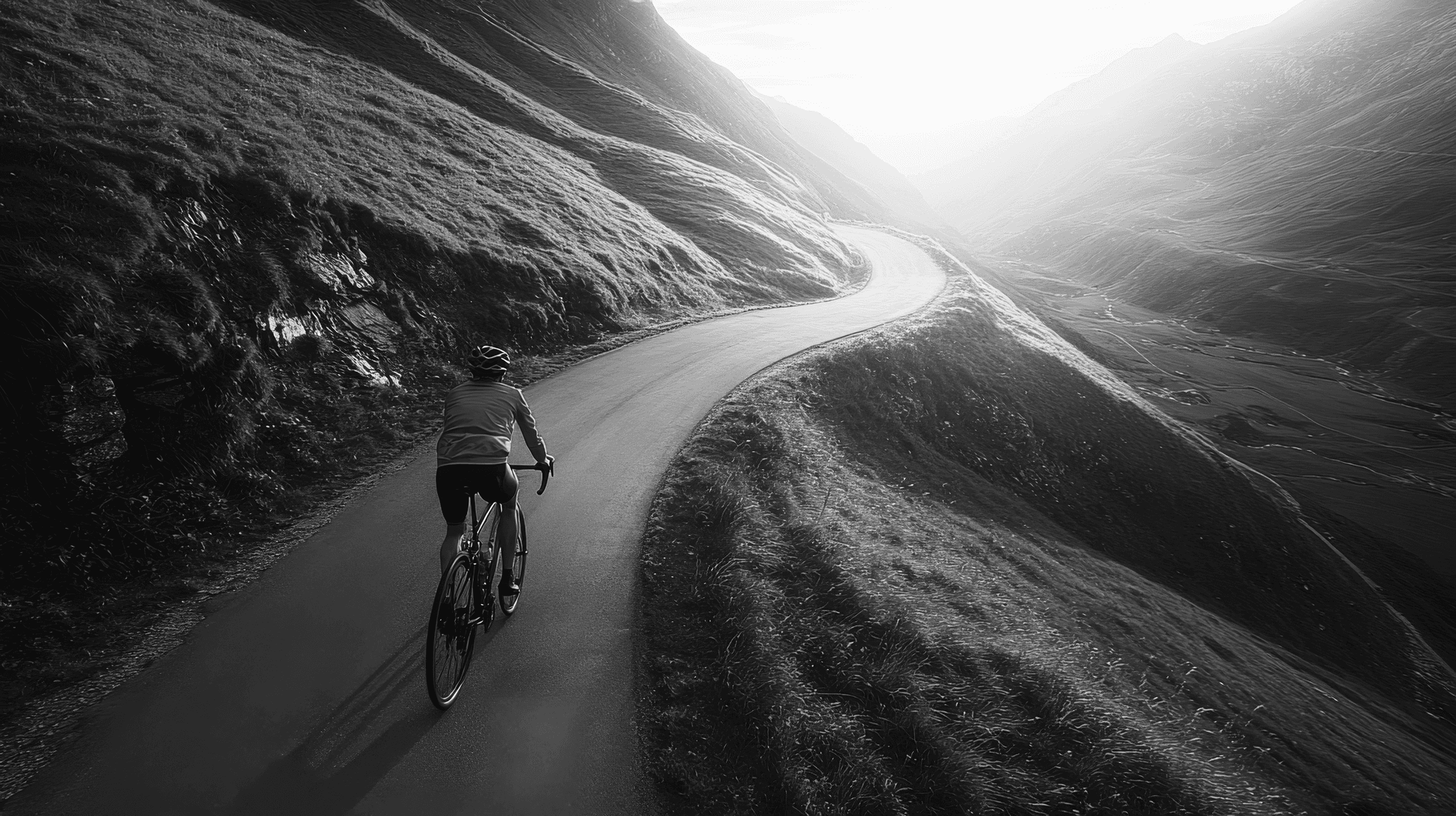 Cyclist on winding mountain road at sunset