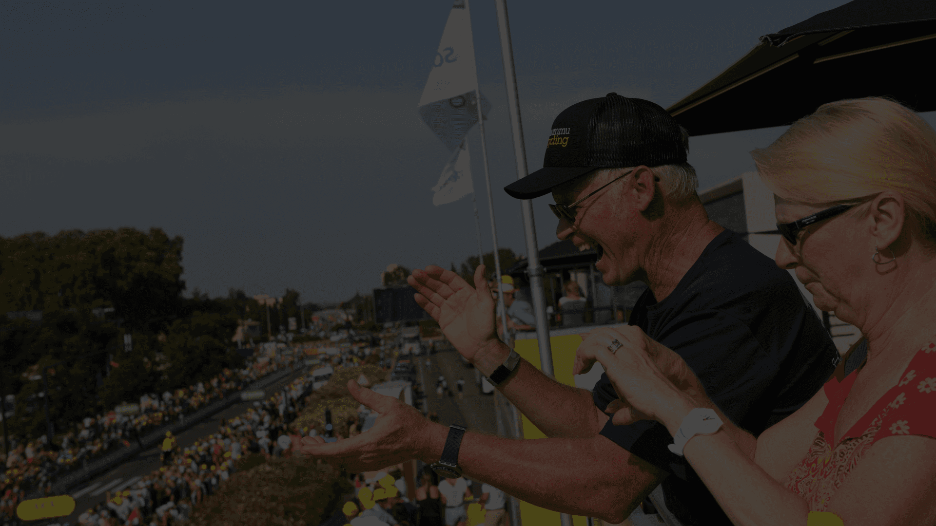 Enthusiastic cycling fans cheering from a balcony.